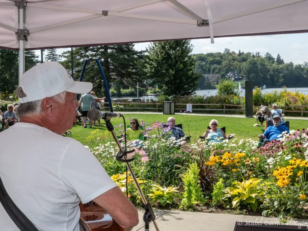 Un homme joue d ela guitare devant des specctateurs rassemblés