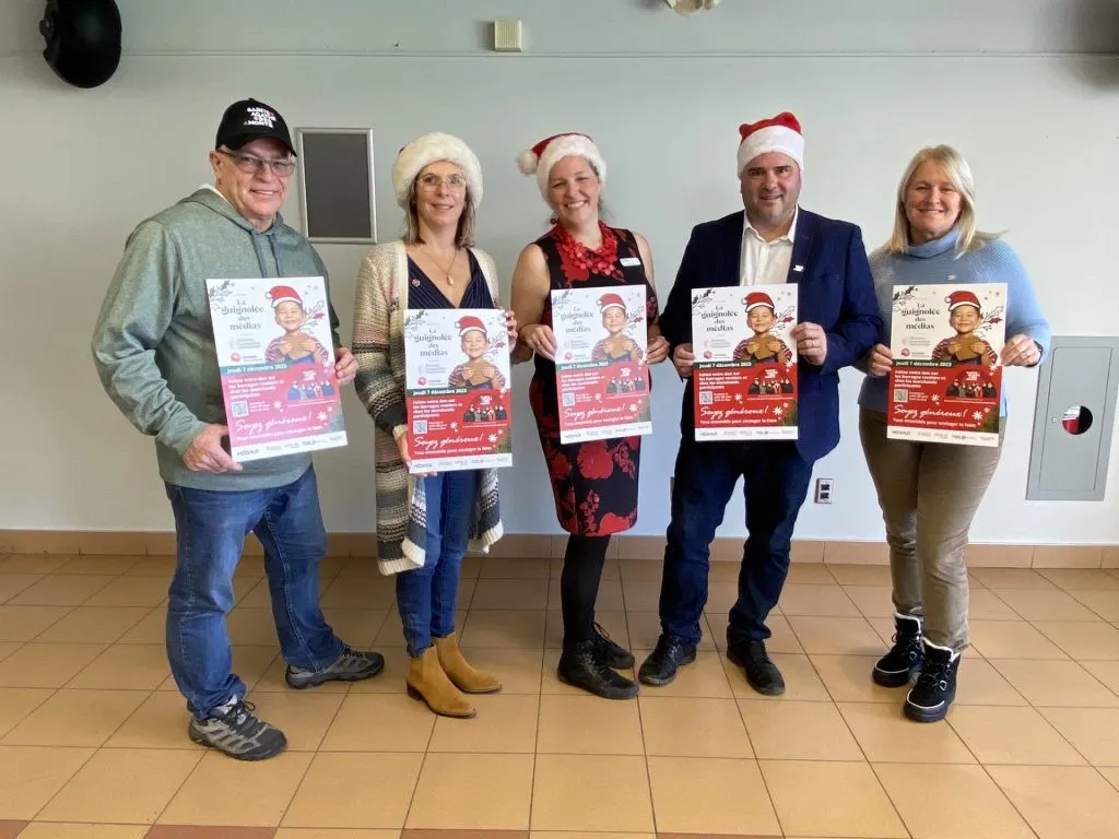 5 personnes avec des affiche de la Guignolée des médias