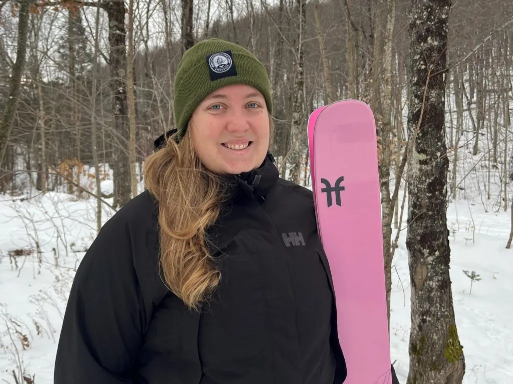Une jeune femme dehors se tient debout avec ses skis