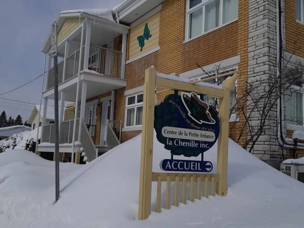 Une affiche de garderie devant un bâtiment l'hiver