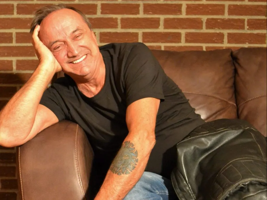 Un homme souriant appuyé sur un accoudoir