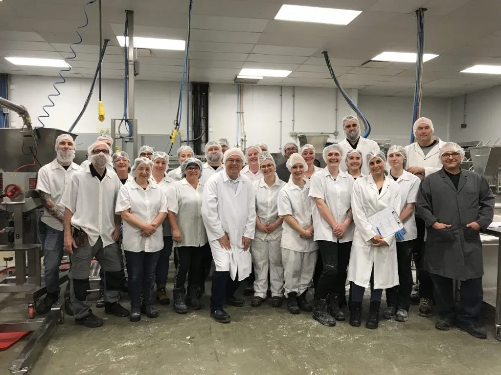 Des gens dans une usine habillés de blanc avec des filets sur la tête
